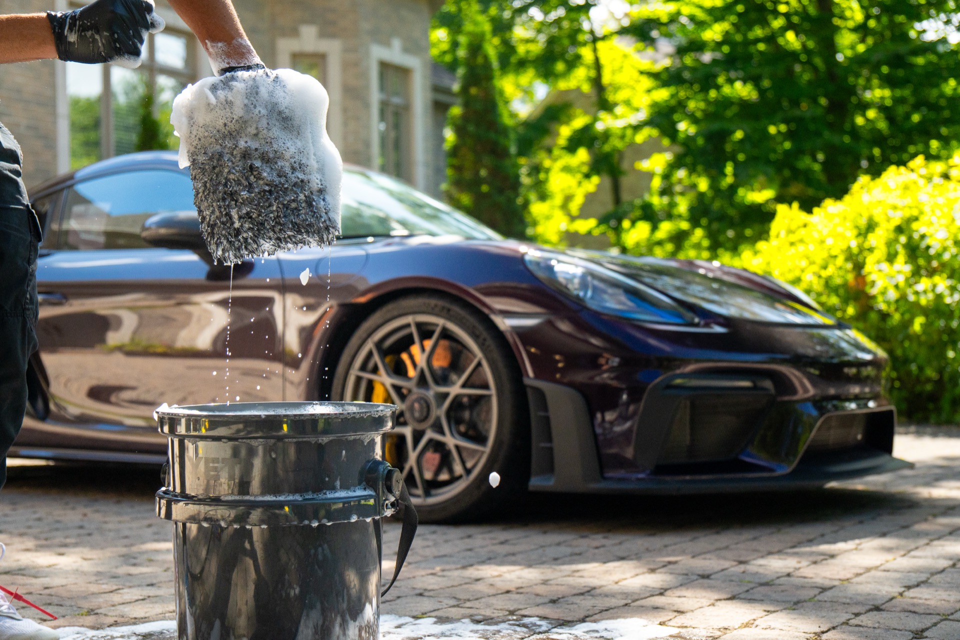 Hand wash detailing a Porsche in the driveway